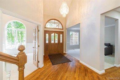 Foyer entrance with wood finished floors, high vaulted ceiling, and a chandelier