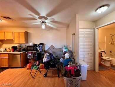 Kitchen featuring light wood-type flooring, light countertops, a textured ceiling, a textured wall, and stainless steel dishwasher