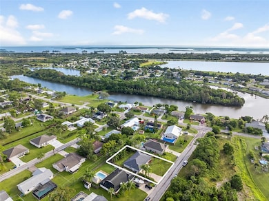 Aerial view of property and surrounding area with property parcel outlined, nearby suburban area, and a nearby body of water