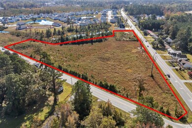 Aerial perspective of suburban area with property parcel outlined and a nearby body of water