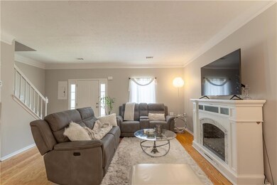 Living area with light wood-style floors, stairs, crown molding, and a fireplace
