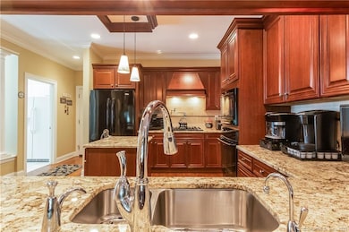 The kitchen has a Viking stove top, with a decorative range hood, Bosch dishwasher, built-in electric oven and a microwave oven above.