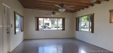 Open concept living and dining room with beautiful wood beamed ceiling and terrazzo floors