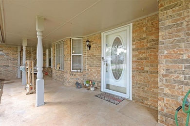 Doorway to property featuring brick siding and a porch