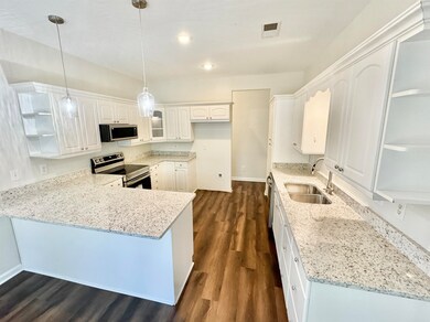Kitchen featuring white cabinets, light stone coun