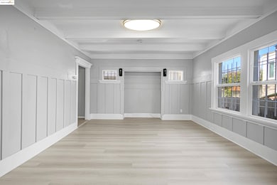 Empty room with a decorative wall, light wood-style floors, a wainscoted wall, and beam ceiling