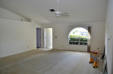 Empty room with lofted ceiling, carpet floors, and ceiling fan