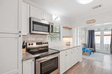 A beautifully renovated kitchen awaits with white cabinets, 