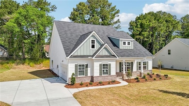 View of front of home featuring brick siding, covered porch, a front yard, board and batten siding, and concrete driveway