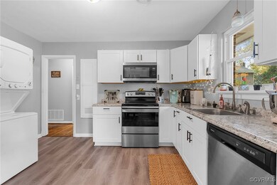 Kitchen featuring white cabinetry, sink, stacked w