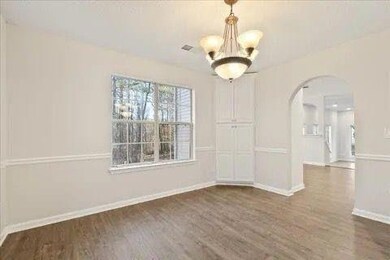 Dining area with arched walkways, a chandelier, wood finished floors, and baseboards