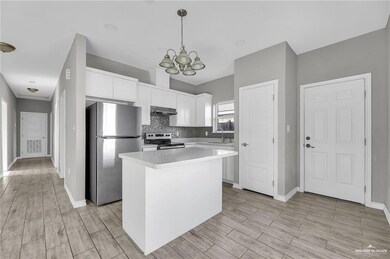 Kitchen with light countertops, decorative backsplash, appliances with stainless steel finishes, white cabinets, and under cabinet range hood