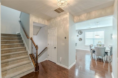Stairway with wood-type flooring, a chandelier, and baseboards