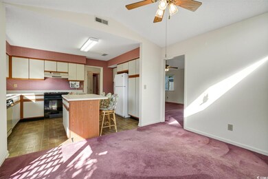 Kitchen with black gas range oven, freestanding refrigerator, a ceiling fan, under cabinet range hood, and lofted ceiling