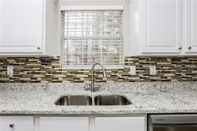 Kitchen featuring a sink, backsplash, white cabine
