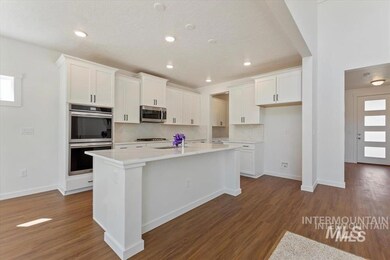 Kitchen with appliances with stainless steel finishes, white cabinets, a kitchen island with sink, dark wood finished floors, and recessed lighting