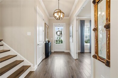 Foyer entrance featuring ornamental molding, healthy amount of natural light, dark wood finished floors, a chandelier, and stairs