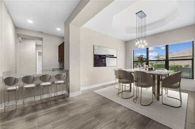 Dining room featuring baseboards, recessed lighting, a raised ceiling, a chandelier, and light wood-style flooring