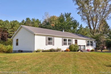 Single story home with a front yard, roof with shingles, and view of scattered trees