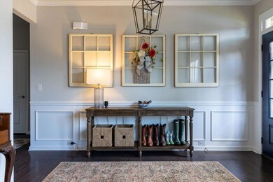 Detailed view of a decorative wall, crown molding, wood finished floors, wainscoting, and a chandelier