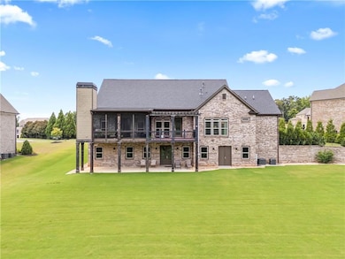 Back of house with a patio area, a yard, stone siding, a sunroom, and a chimney