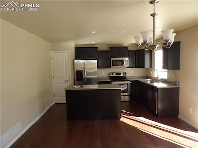 Kitchen with stainless steel appliances, a chandelier, a center island, dark wood-type flooring, and recessed lighting