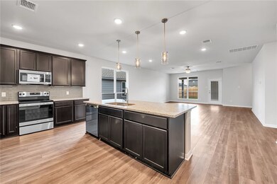 Kitchen featuring appliances with stainless steel finishes, hanging light fixtures, dark brown cabinetry, backsplash, and recessed lighting