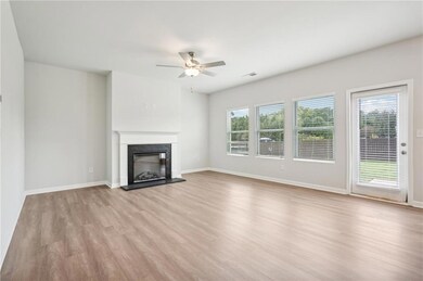 Unfurnished living room with light wood-type flooring, healthy amount of natural light, a fireplace, and a ceiling fan