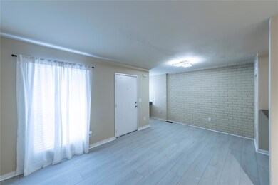 Unfurnished room with brick wall and light wood-st