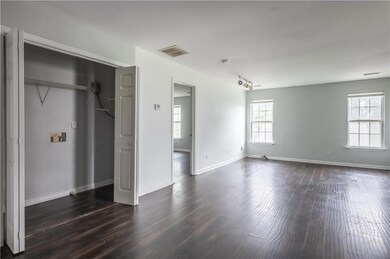 Unfurnished bedroom featuring dark wood-style flooring, multiple windows, and a closet