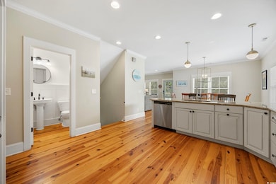 Kitchen with dishwasher, ornamental molding, light wood-type flooring, recessed lighting, and hanging light fixtures