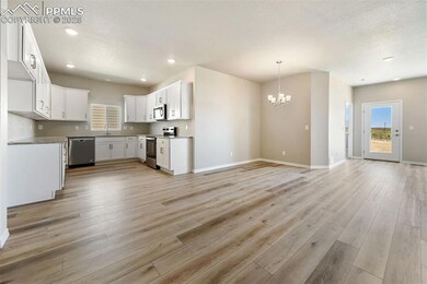 Kitchen featuring stainless steel appliances, open floor plan, a chandelier, light wood finished floors, and a sink