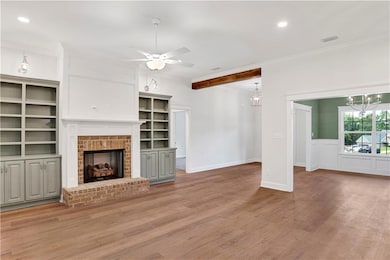 Unfurnished living room featuring recessed lighting, crown molding, a ceiling fan, wood finished floors, and a brick fireplace