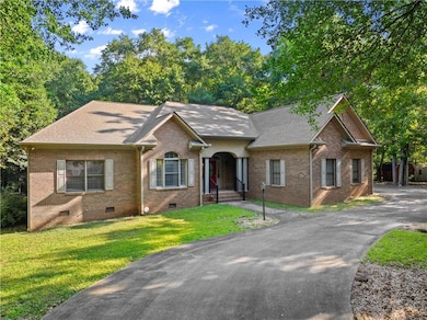 View of front of home featuring crawl space, brick siding, roof with shingles, a front yard, and driveway