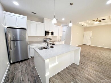 Kitchen featuring appliances with stainless steel finishes, recessed lighting, white cabinetry, an island with sink, and wood finished floors