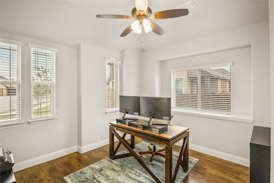Office with dark wood-style flooring and a ceiling fan