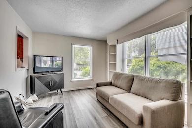 Living room with a textured ceiling, wood finished floors, and baseboards