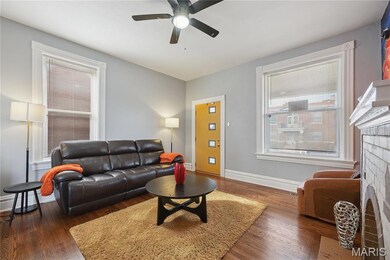 Living room with a fireplace, wood finished floors, and a ceiling fan