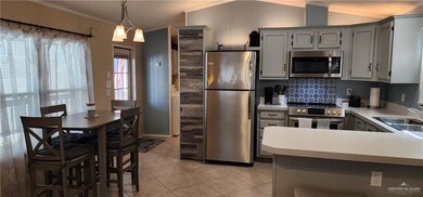 Kitchen with light tile floors, stainless steel appliances, crown molding, sink, and pendant lighting