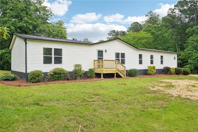 Rear view of house with a deck, a lawn, and crawl 
