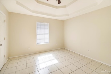 Tiled spare room featuring a raised ceiling and ceiling fan