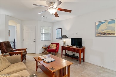 Living area featuring ceiling fan, arched walkways, and light tile patterned floors