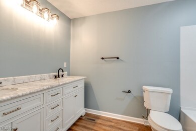 Bathroom with wood-type flooring, double sink vanity, and toilet