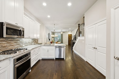 Kitchen featuring stainless steel appliances, a peninsula, dark wood-style floors, white cabinets, and recessed lighting