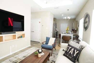 Living room featuring light tile patterned floors, visible vents, a skylight, baseboards, and a notable chandelier