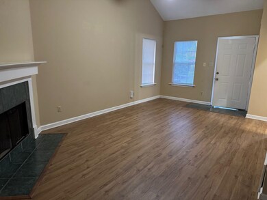 Unfurnished living room featuring dark wood-style flooring, a tile fireplace, baseboards, and high vaulted ceiling