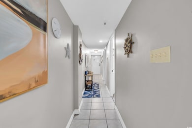Hallway with light tile patterned floors and baseb
