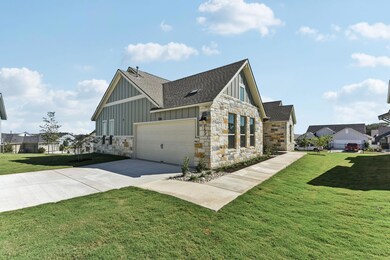 View of property exterior featuring roof with shingles, board and batten siding, a lawn, stone siding, and driveway