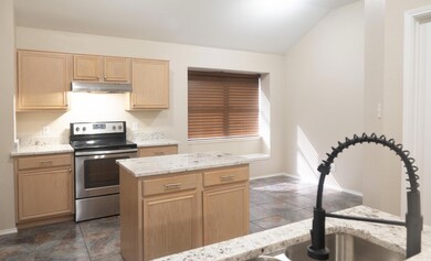 Kitchen featuring electric range, lofted ceiling, 