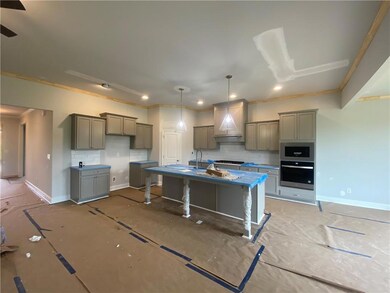 Kitchen with appliances with stainless steel finishes, backsplash, an island with sink, gray cabinetry, and ornamental molding